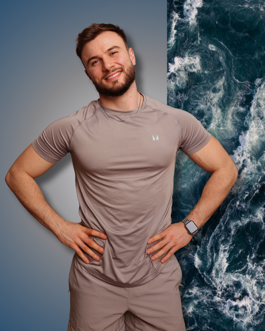 Man in a brown athletic outfit standing against a gradient background with ocean waves.